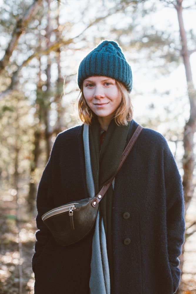 Red haired woman in hat and scarf surrounded by trees