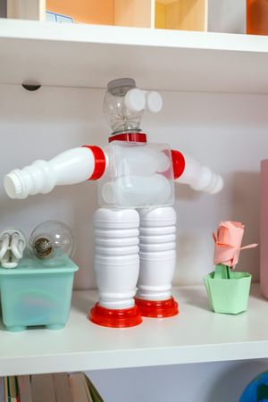 Recycled toy robot made with plastic packages on shelf in classroom