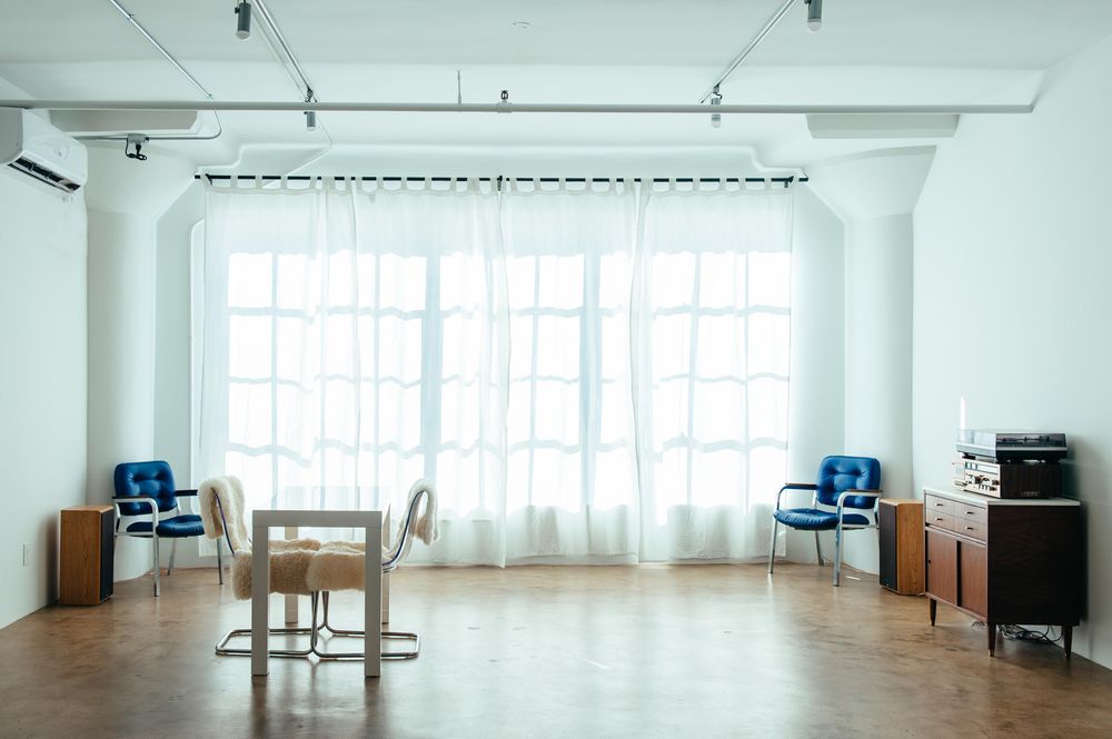 Studio loft with large windows covered by curtains and vintage furniture