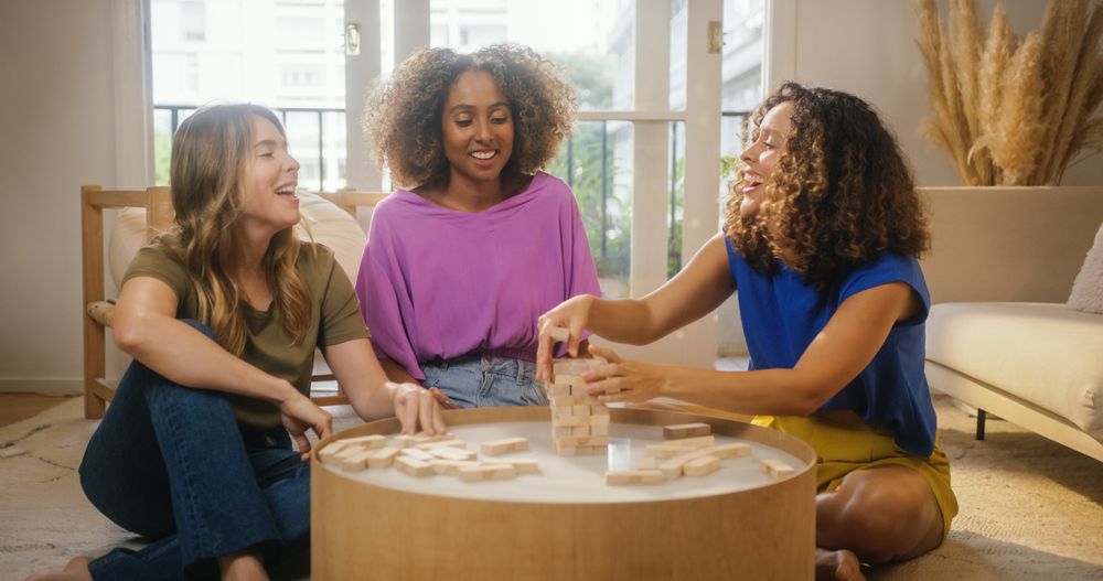 Group of Young Female Friends Playing a Physical Skill Blocks Game at Home in Cozy Sunny Living Room.