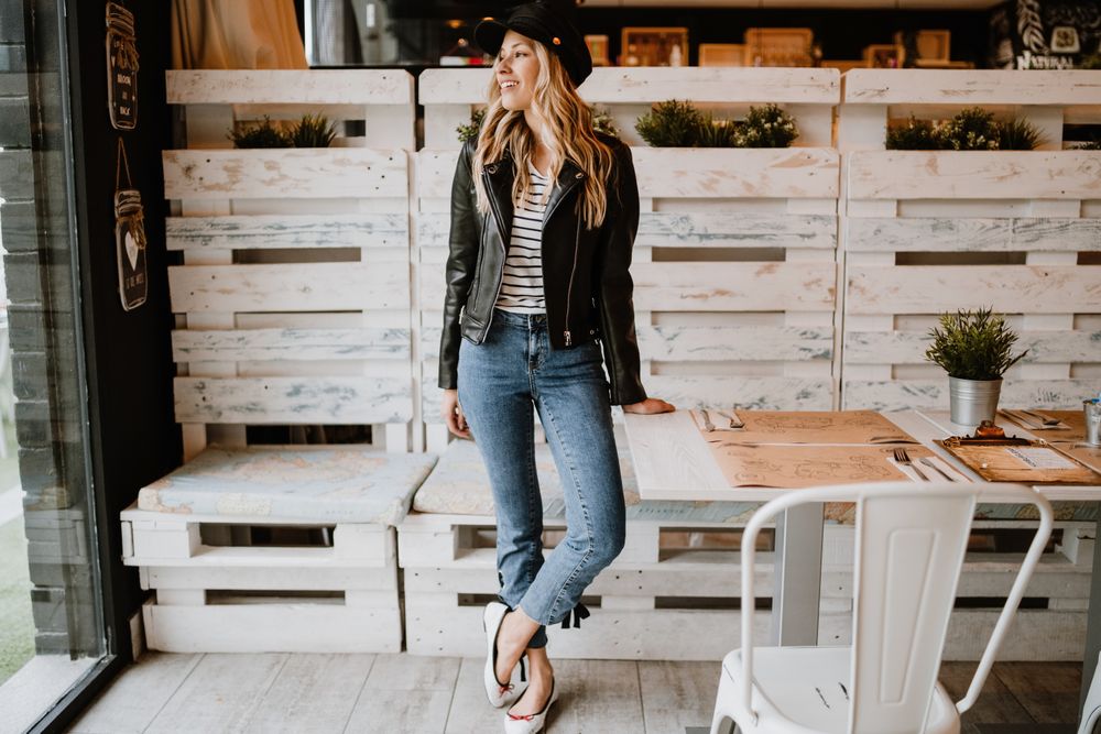 Casual stylish woman standing at table in cafe