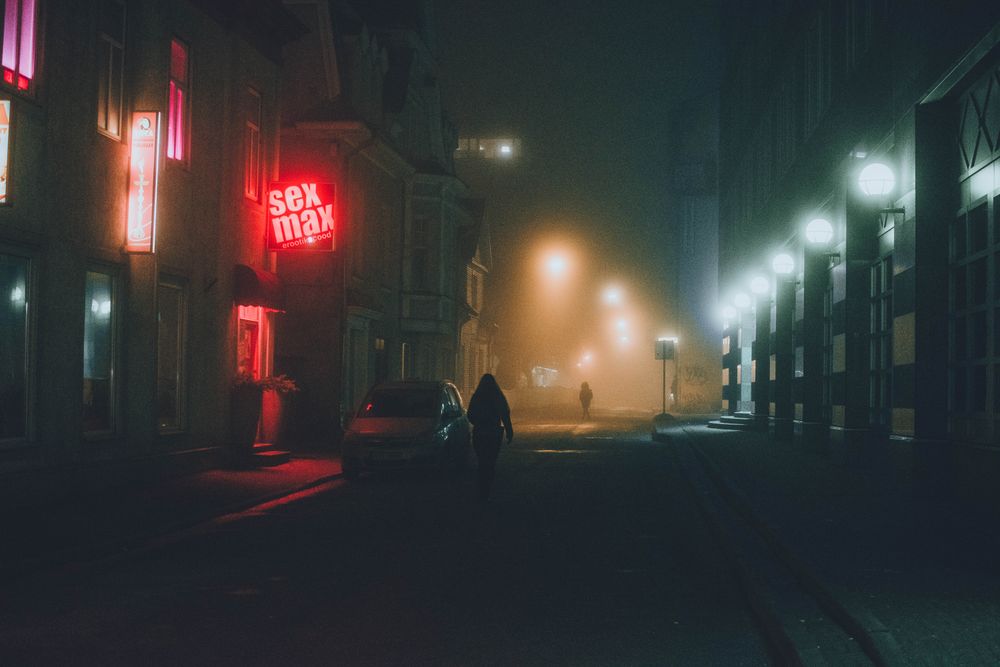 Silhouette of person walking down the street at night