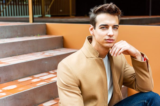 Man in fall coat sitting on staircase outside