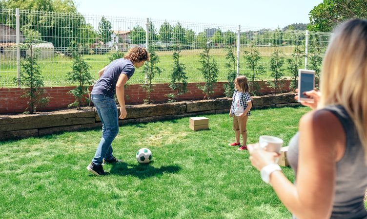Mother taking photo of her husband and son playing