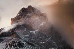 Harsh mountain snowy peak shrouded in fog