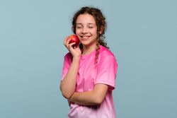 Girl with eyes closed, holding an apple.