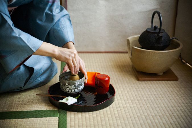 Japanese woman in kimono sitting on ground preparing tea
