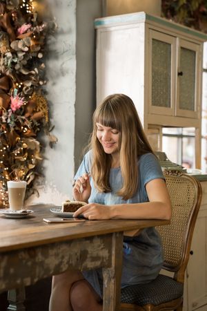 Cheerful woman using a phone in cafe