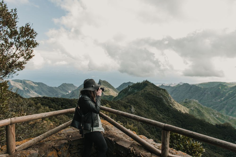 Young stylish woman taking photo on camera of wonderful mountains