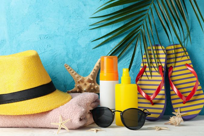 Summer vacation accessories against blue background, space for text