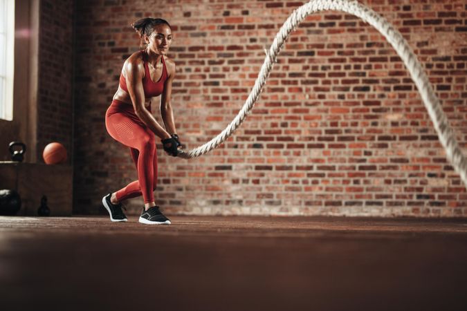 Sporty woman using one battle rope for workout