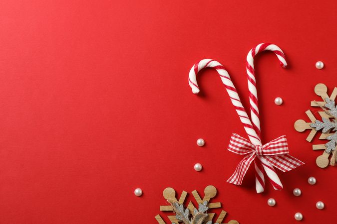 Candy canes and decorative snowflakes on red background, top view