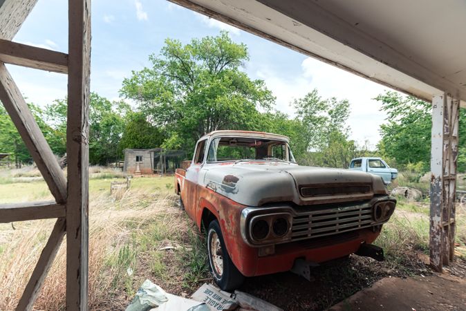 Old rusty car by wooden fence in rural area