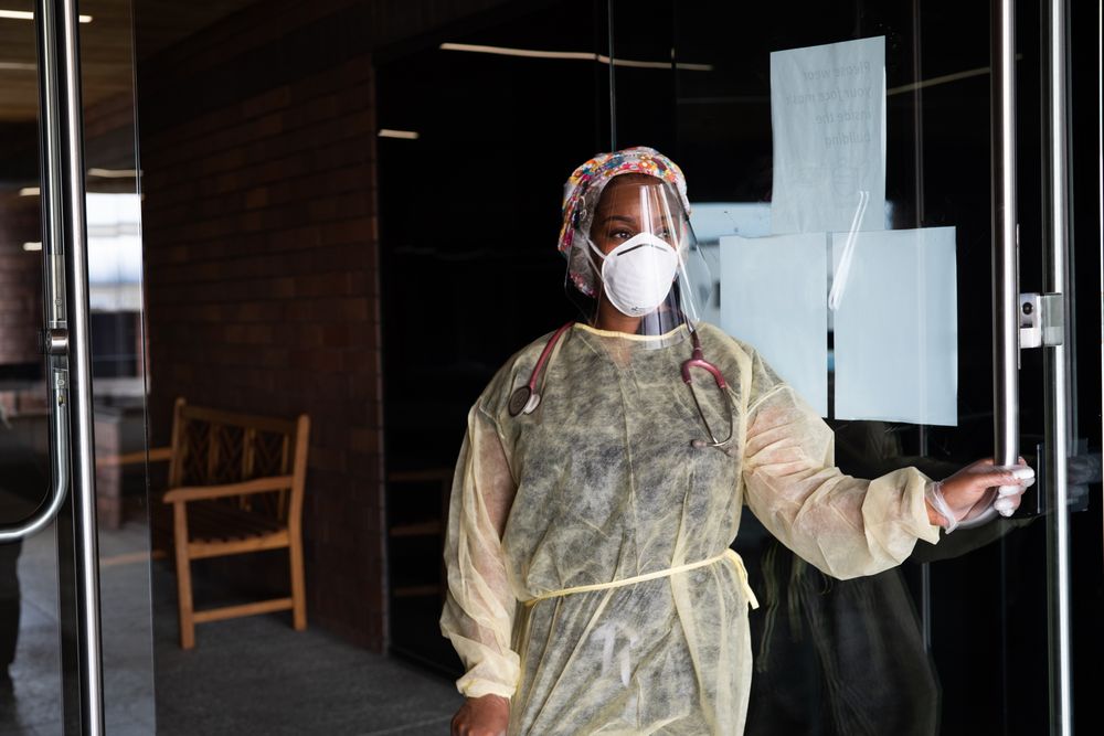 Woman nurse looks out of doorway while wearing PPE