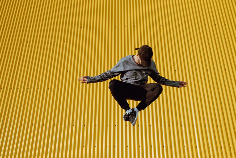 Man jumping near yellow wall