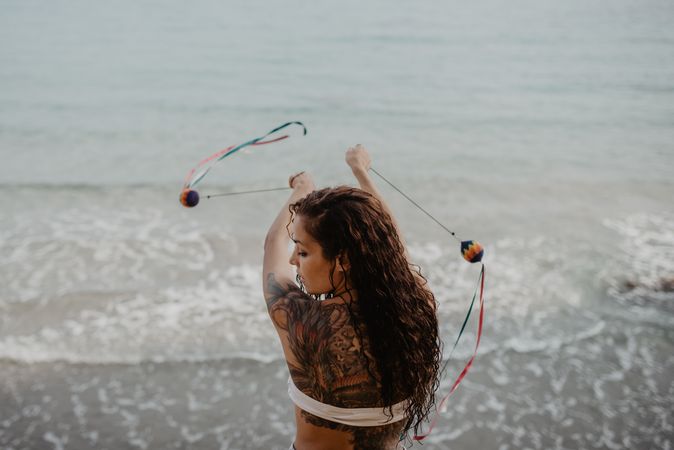 Tattooed woman dancing with balls near sea