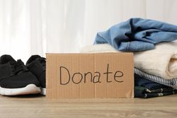 Text Donate and clothes on wooden background. Donation concept