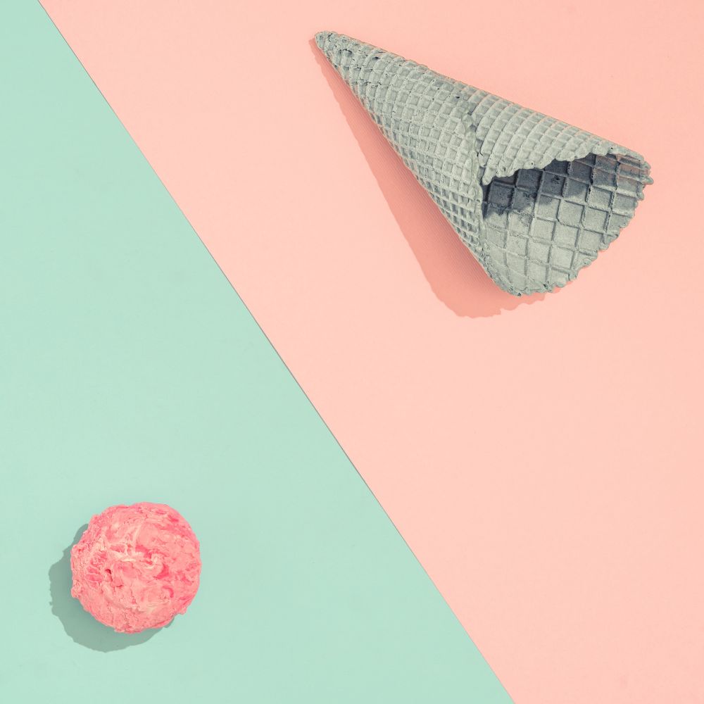 Ice cream cone with scoop of ice cream on pastel pink and blue background