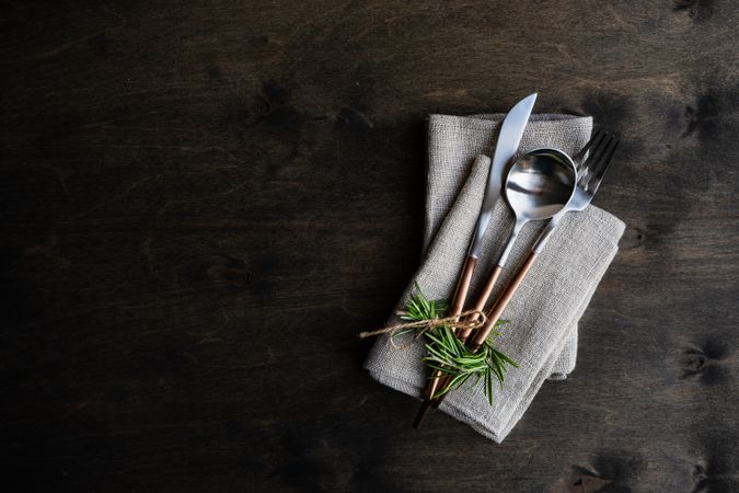 Cutlery set on grey napkin with rosemary garnish