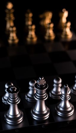Silver chess pieces against blurred golden backdrop.
