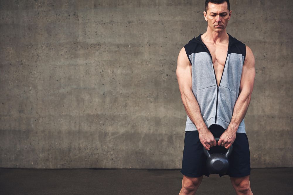 Intense man in vest holding kettlebell