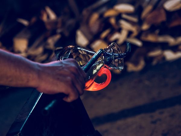 Anonymous master making glass carafe in factory