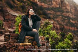 Female traveler sitting on a stones with mountain in the background 4AvBWb