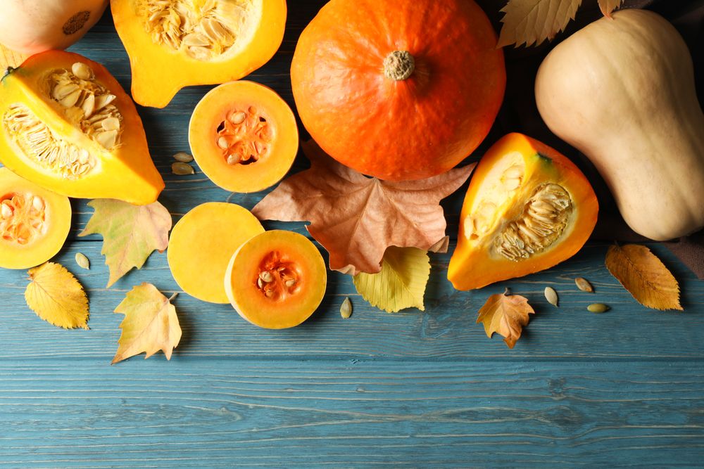 Composition with pumpkin, squash, seeds and leaves on wooden background