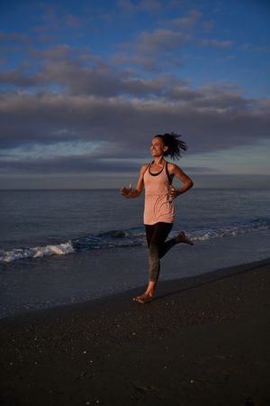 Positive Hispanic woman running along sea