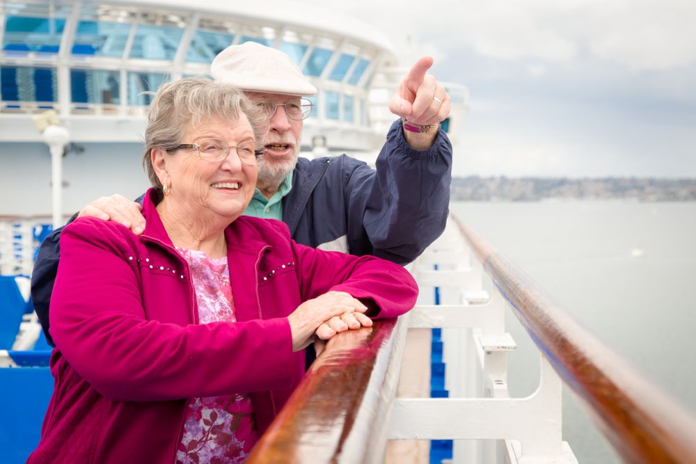 Content Older Adult Couple Enjoying The View From Their Passenger Cruise Ship Railing.