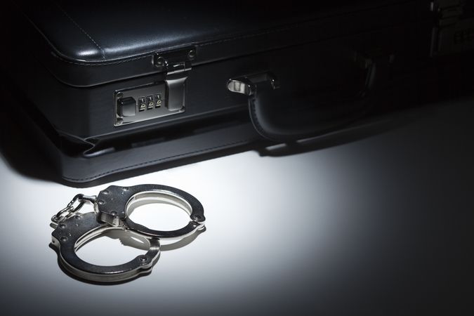 Pair of Handcuffs and Briefcase Under Spot Light