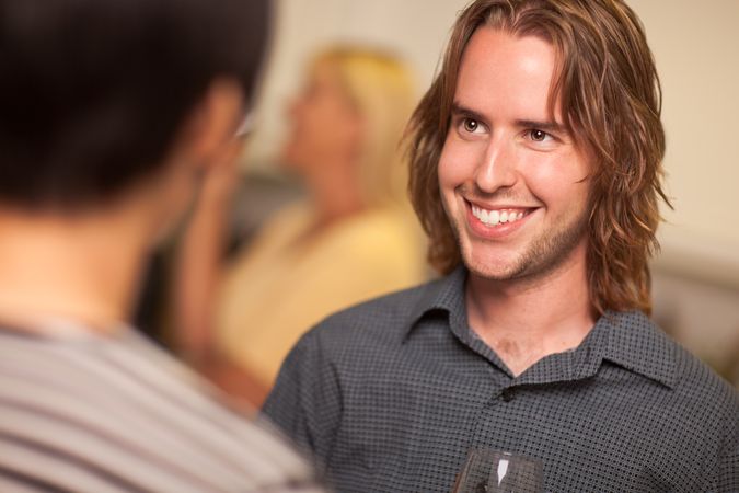 Smiling Young Man with Glass of Wine Socializing