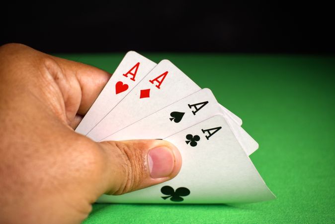 adult hand holding aces poker cards