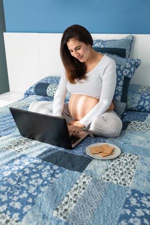Pregnant woman talking on video chat on laptop