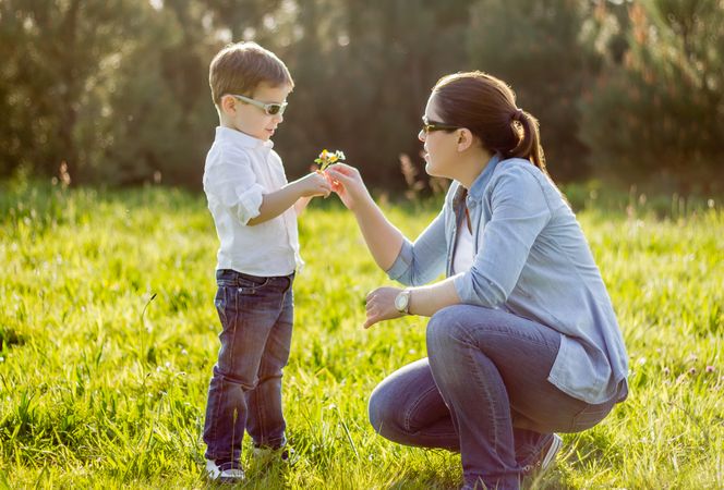 Son giving a bouquet of flowers to his mother in a field