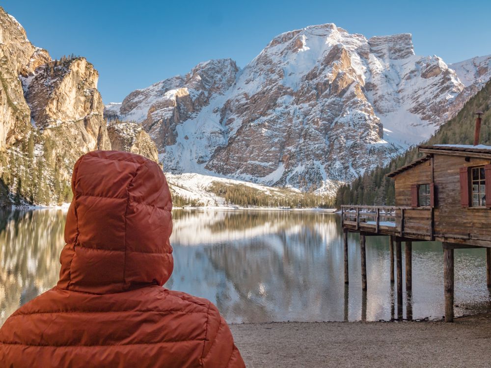 Unrecognizable person in warm jacket standing and looking at serene landscape