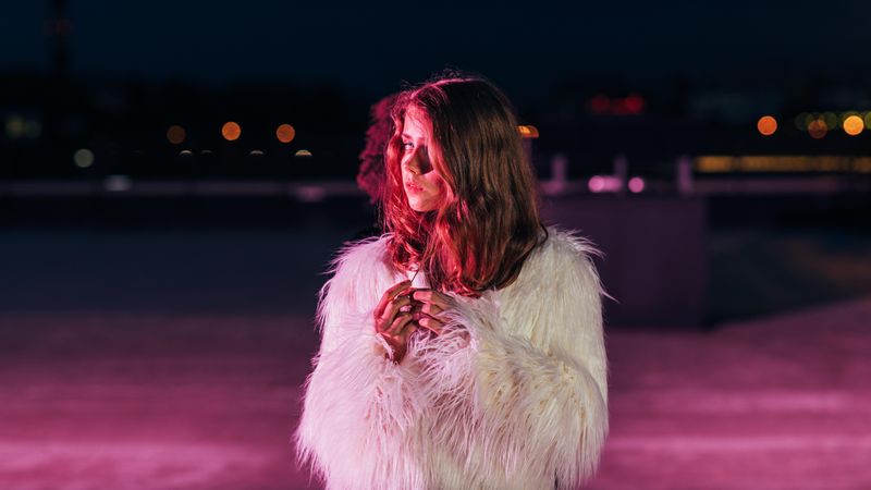 Woman in shaggy faux fur in moody red light at night