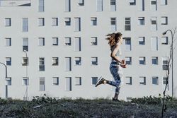Woman in sportswear running near building