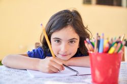 Inspired little child writing on paper with pencil