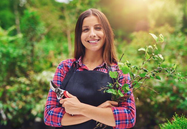 Smiling florist pictured with branches and shears