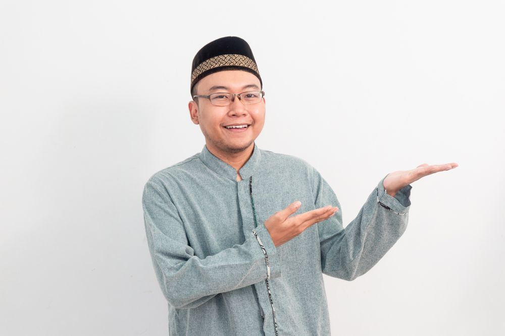Asian Muslim man smiling showing product gesture in Ramadan