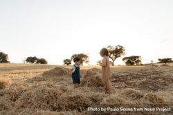 Two children standing in a field with hay 5pxWg5