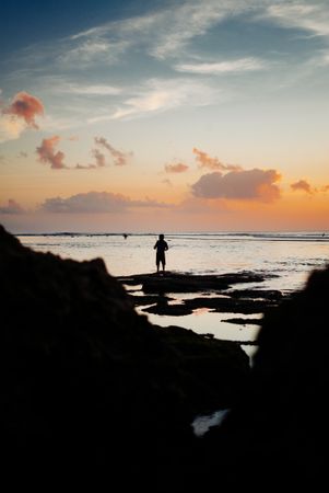 Man fishing on Bali beach at sunset