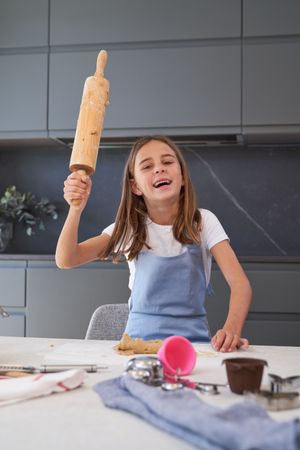 Content girl with rolling pin in kitchen
