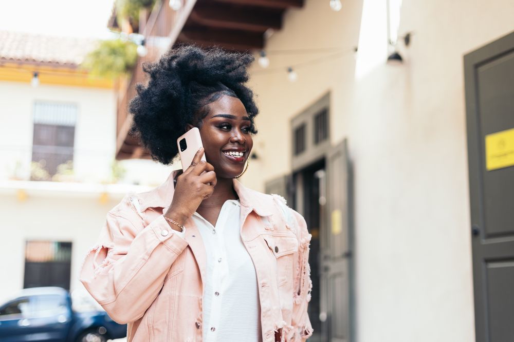 Stylish Black woman walking on the city street talking on the phone