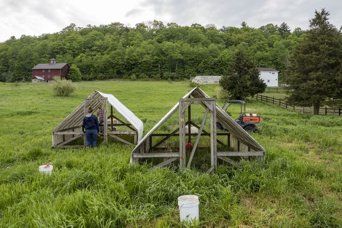 Copake, New York - May 19, 2022: Two small chicken coops being built in field by man and woman