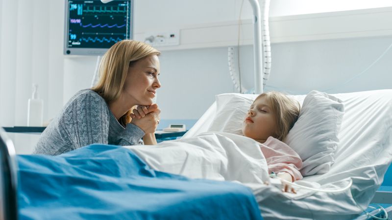 Cute Little Girl Sleeps on the Bed in the Children's Hospital, Her Mother Sits Beside, Worrying but Hopeful