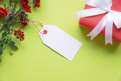 Top view of red flowers with blank gift tag and wrapped present