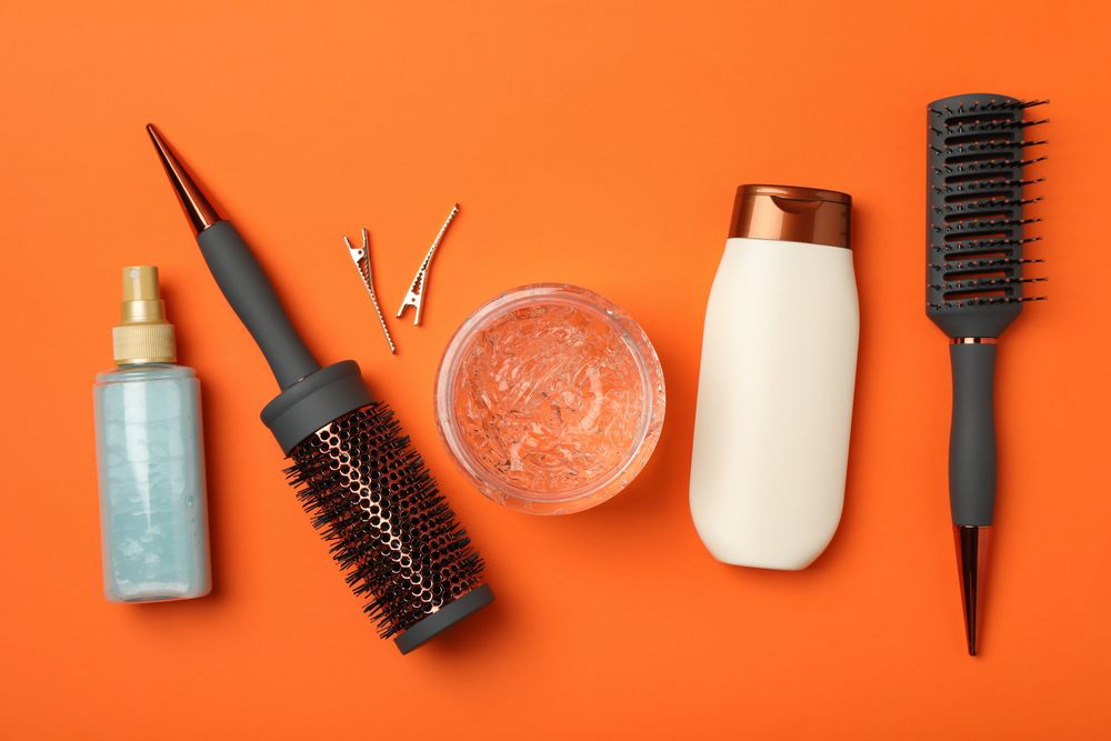Composition with hairdresser accessories on orange background, top view