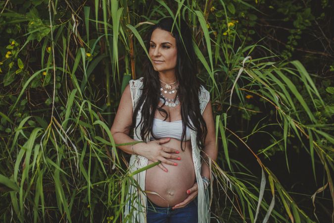 Pregnant woman touching belly in park